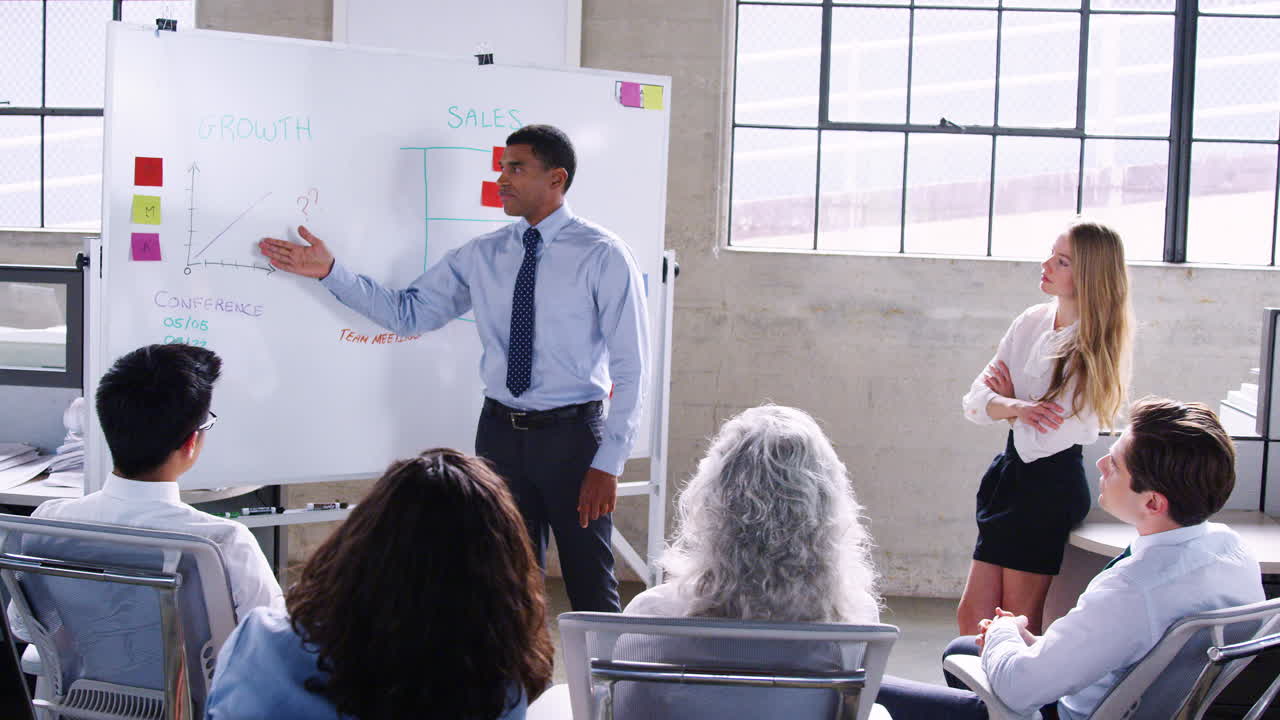 hombre de negocios de raza mixta por una pizarra durante la presentación