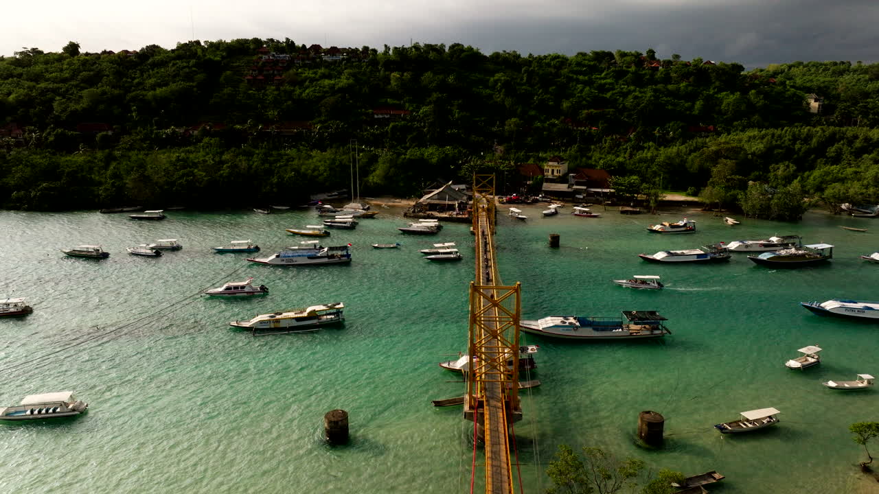 el famoso puente amarillo en indonesia que conecta las islas nusa lembongan y nusa ceningan en bali con barcos flotando en el agua turquesa del océano