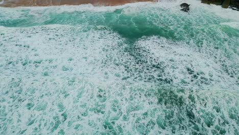 drone view beautiful waves rolling to sandy shoreline. water foaming on seashore