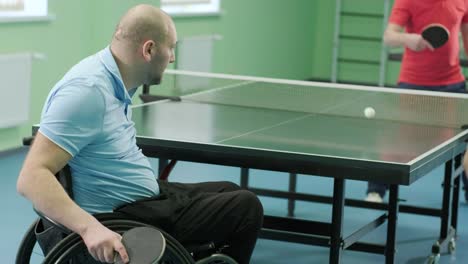 a man in a wheelchair plays ping pong. people with disabilities play table tennis. rehabilitation of the disabled. sport.