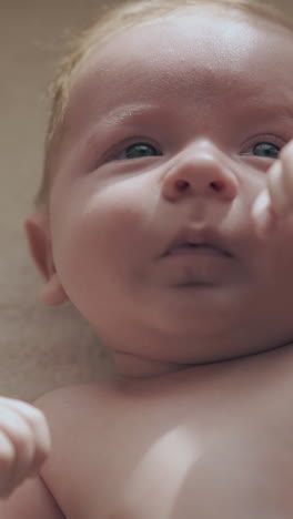 funny infant boy with adorable cheeks and big blue eyes lies on changing table and makes cute faces extreme close view