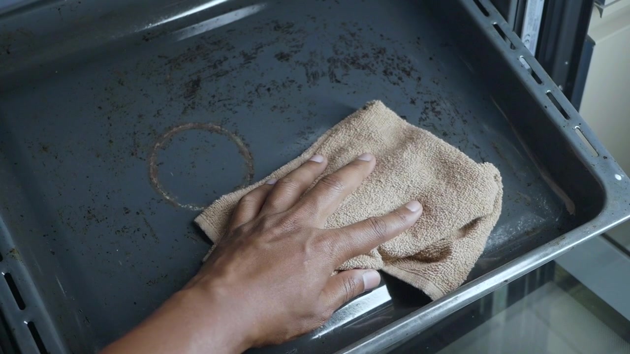 Person Cleaning Dirty Baking Tray with Cloth