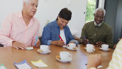 Glückliche-ältere,-Vielfältige-Menschen,-Die-Im-Altersheim-Tee-Trinken-Und-Bingo-Spielen