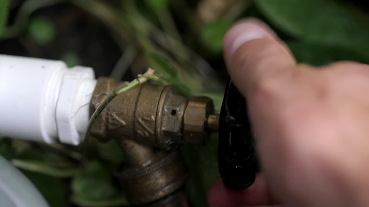 Apertura e chiusura di un rubinetto dell'acqua esterno con tubo da giardino collegato.