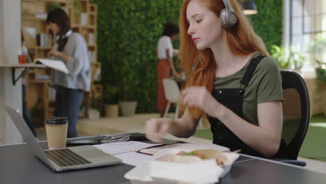 Joven-Mujer-De-Negocios-Caucásica-Escribiendo-Notas-Disfrutando-Del-Estudio-Escuchando-Música-Usando-Auriculares-Estudiante-Trabajando-En-Una-Ocupada-Oficina-Multiétnica