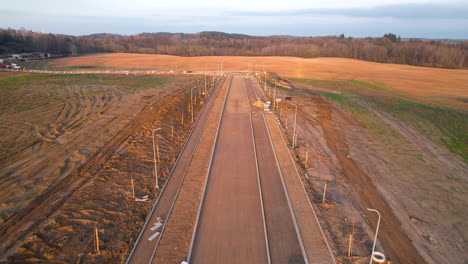 aerial flying over unfinished road infrastructure in countryside during golden hour