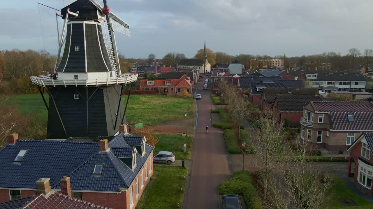 Vista aerea del mulino a vento De Kievit con villaggio e pista ciclabile a Grijpskerk, Groninga, Paesi Bassi