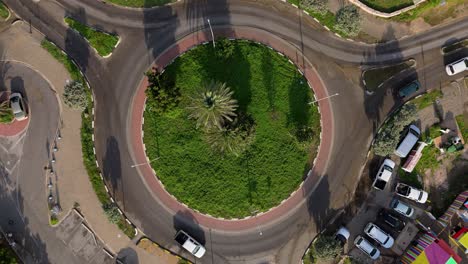 drone rises above roundabout in caribbean, rotating as cars exit the road