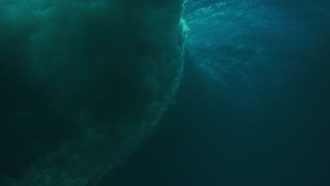 water sprays across wave surface with vortex, view from underwater