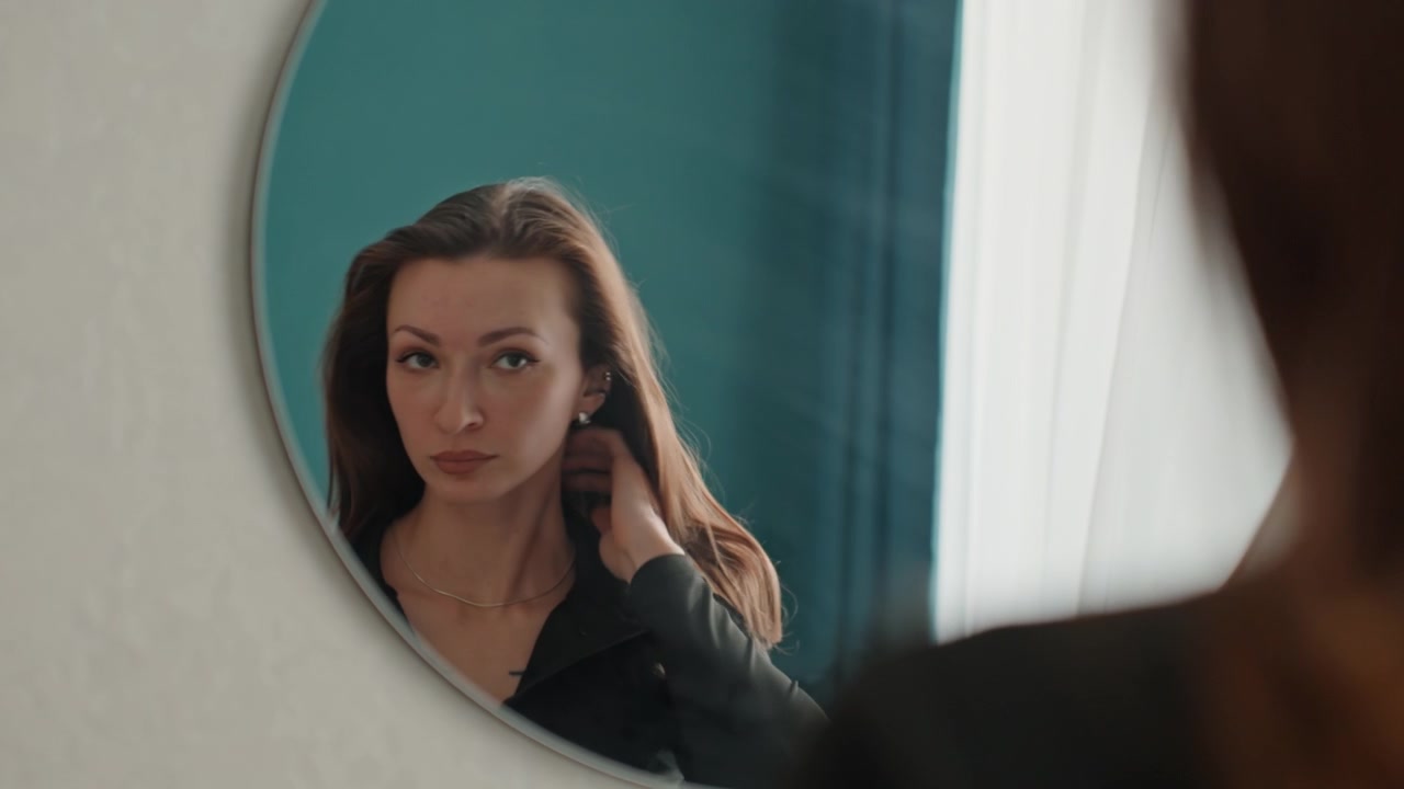 Donne che preparano attentamente le loro routine di bellezza. Si curano meticolosamente osservando il proprio aspetto e organizzano con cura il loro look usando uno specchio e la luce naturale.