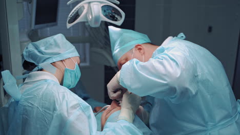 specialist man and female assistant in medical uniform work in dental office. stomatologists are making medical procedure on teeth for patient. oral treatment.