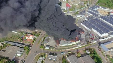 dense and toxic black smoke rising from burning warehouse, scenic shot with drone