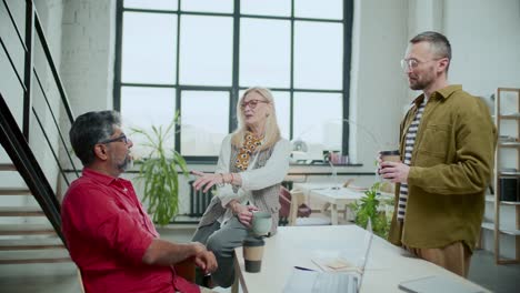 group of diverse colleagues chatting during coffee break in office