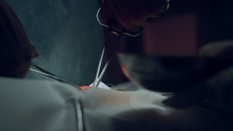 closeup surgeon hands suturing wound with forceps in hospital operating theatre.