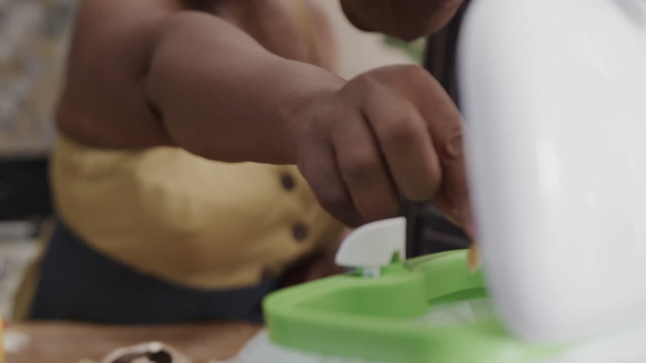 Mid section of senior african american couple throwing food waste out in ktichen in slow motion