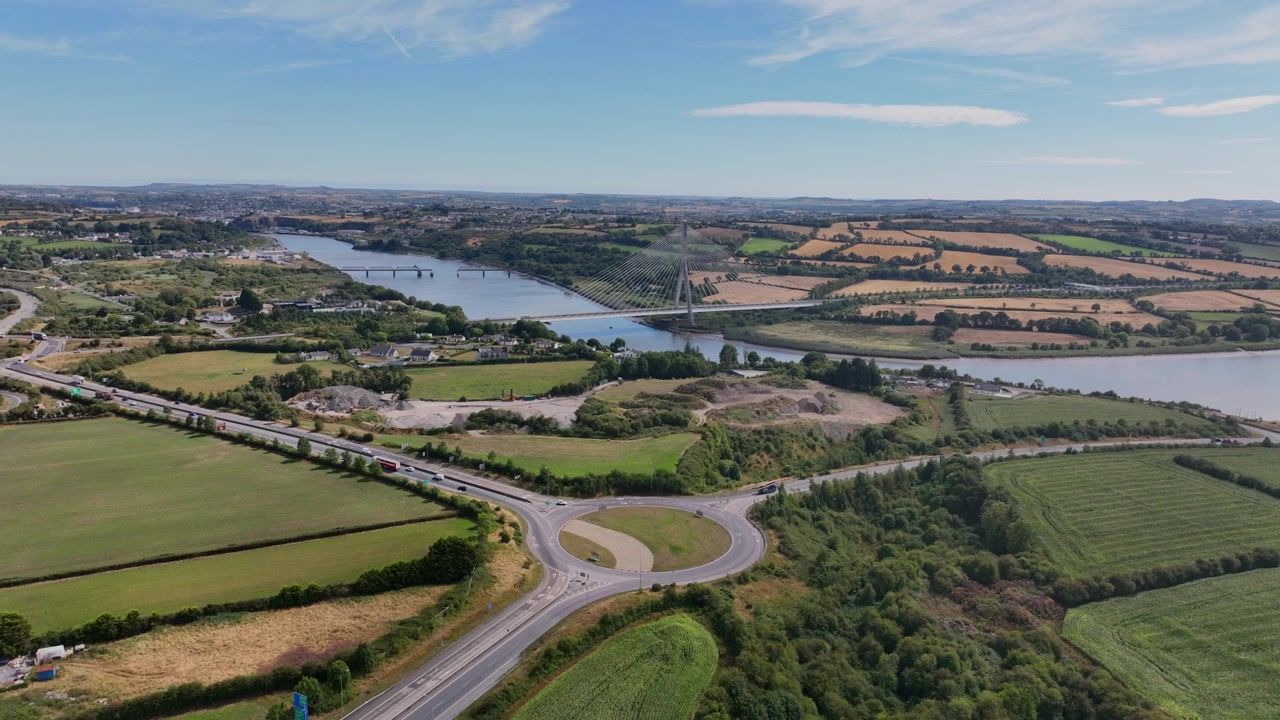 Incredibile ripresa aerea con drone in Irlanda che sorvola l'uscita M9 con panoramica della città di Waterford e del sistema di trasporti sul ponte Thomas Francis Meagher che attraversa il fiume Suir