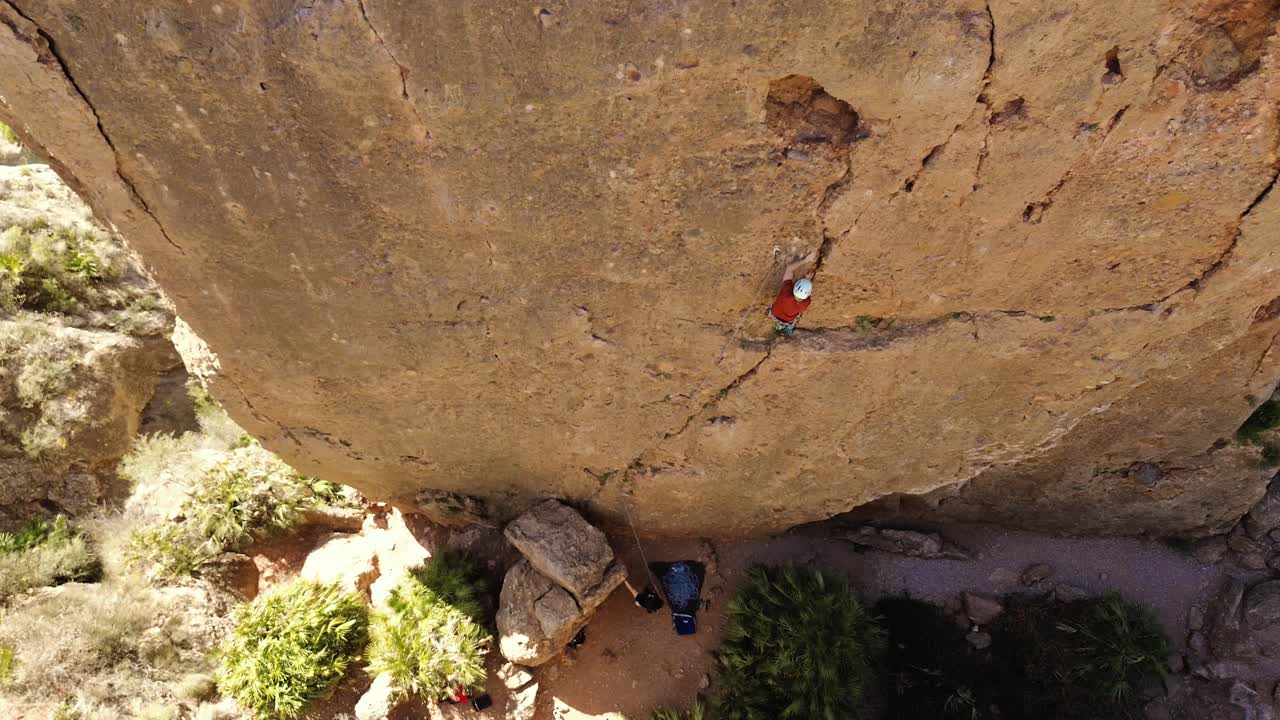 Luftaufnahme eines Mannes beim Felsklettern und eines Sportlers beim Abseilen am Berg in La Panocha, El Valle Murcia, Spanien, mit einer Frau, die sich einen Berg hinabseilt und einen großen Felsen erklimmt.