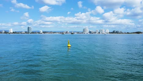 revealing a yellow marine speed limit marker buoy sits anchored in calm waters of a major waterway zone
