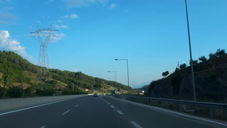 driving car on highway through beautiful valley with hills and electricity poles on a summer day with clear blue sky in albania