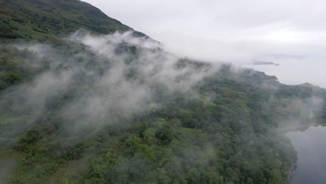 slow motion cinematic shot of the foggy greens on high mountains near a empty pleasant island in a natural background at glen coe, loch etive in scotland