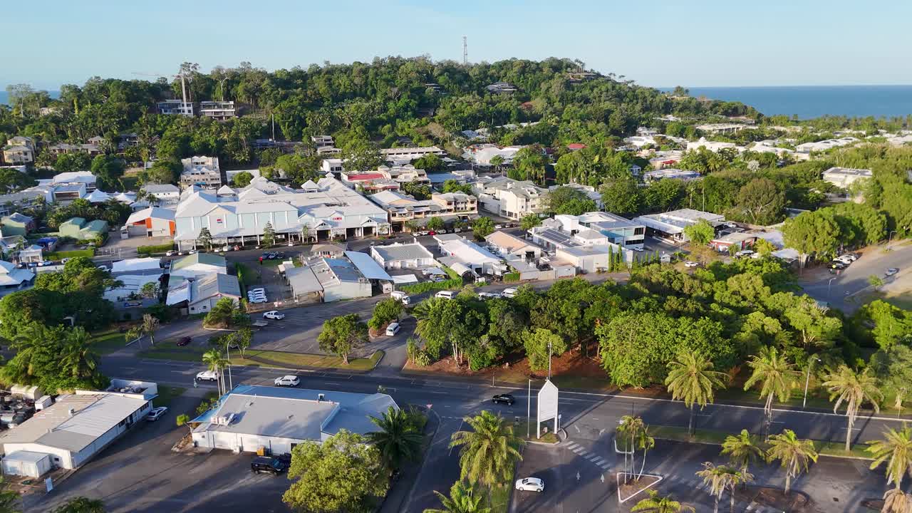 Drone footage captures Port Douglas with lush greenery, coastal views, and vibrant town life under bright daylight
