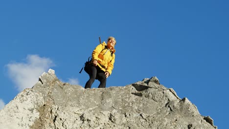 senior woman standing with arms up on a rock 4k