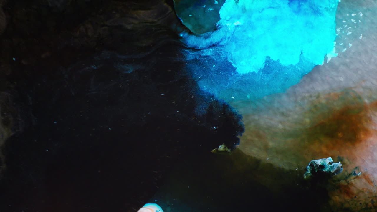 Fusione di inchiostro color turchese con inchiostro nero in un mezzo liquido.