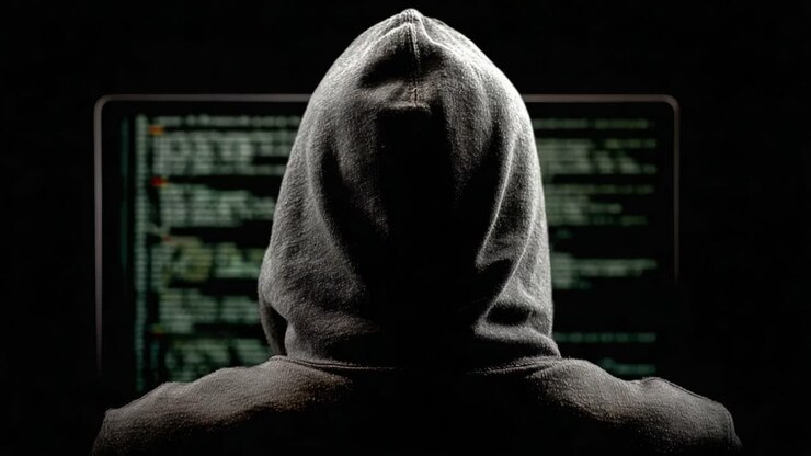 Misterioso programmatore con felpa con cappuccio che analizza codice complesso su uno schermo scuro, enfatizzando l'intricato mondo della programmazione e le sfide della sicurezza informatica