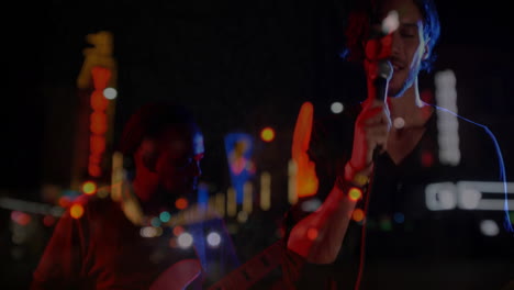 singer holding microphone and guitarist playing guitar on city street night with music neon effects