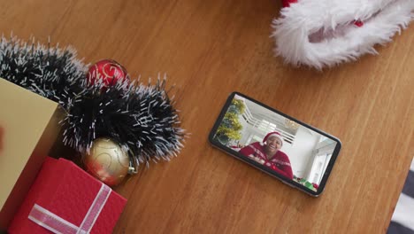 Smiling-african-american-woman-with-santa-hat-on-christmas-video-call-on-smartphone