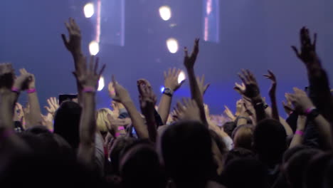 people with hands up at the rock concert view with stage lights