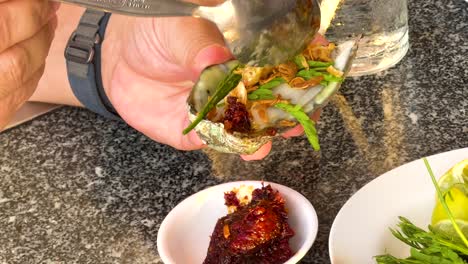 hands preparing oysters with toppings and sauce