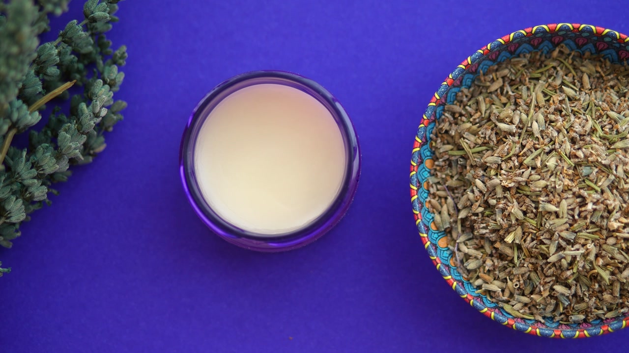 Natural Lavender Cream and Dried Buds with Fresh Sprig on Purple Background