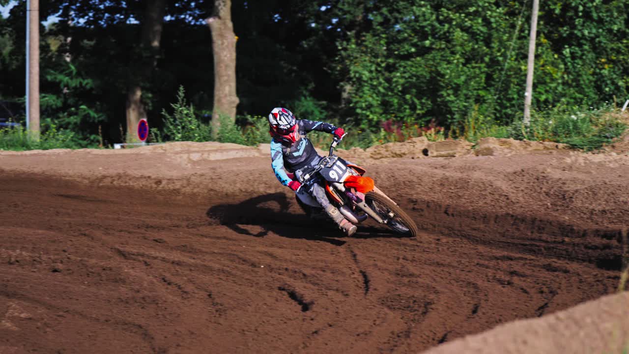 베를린 경쟁에서 느린 동작으로 흙 트랙에서 매력적인 회전을 통과하는 모토크로스 레이서