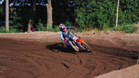 corredor de motocross pasando giro con curvas en pista de tierra en cámara lenta en competencia de berlín