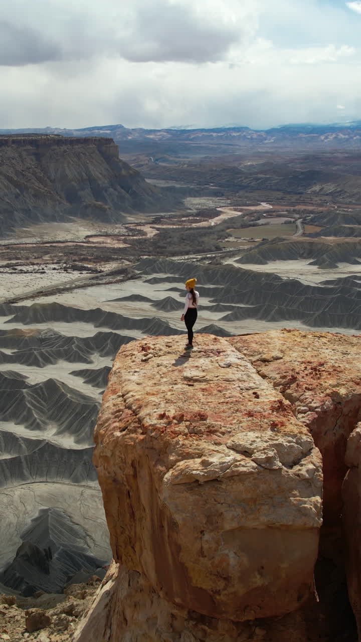 Woman standing on a cliff overlooking a vast desert canyon