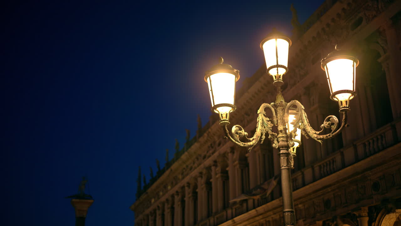 Close up of lighted street lamps in the evening, with people moving in Venice, Italy
