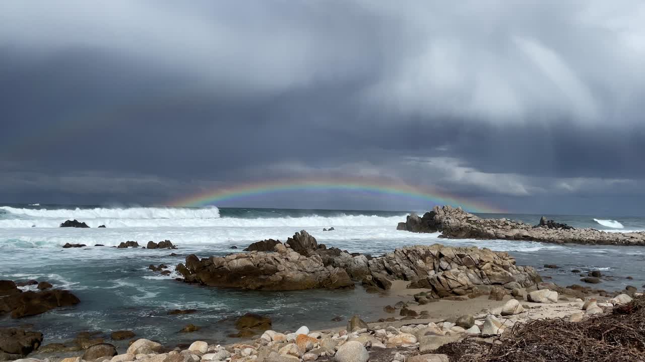 arco iris en el horizonte visto desde la playa en un día tormentoso