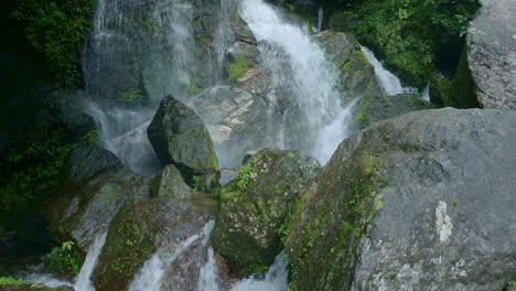 waterfall splashing on rocks in jungle scenery, small waterfalls landscape in rugged rocky scene in the himalayas in nepal with water falling and splashing over rocks