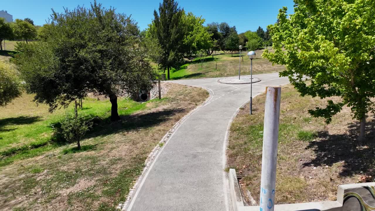 Drone footage flying along a bicycle lane in a small park