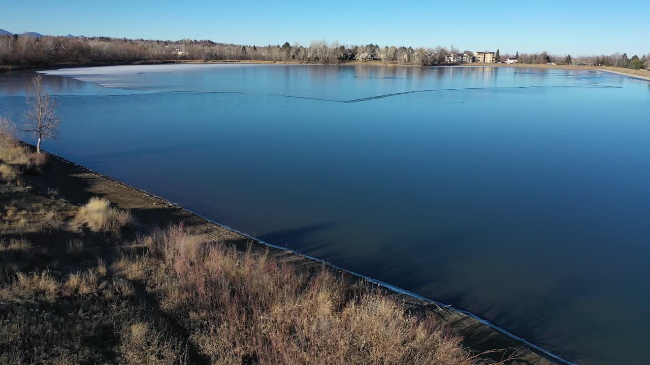 un vuelo como de pájaro sobre un lago helado al oeste de denver captura un día de otoño bañado por el sol