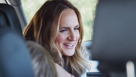 mother turning round to talk to children in back seat on car journey