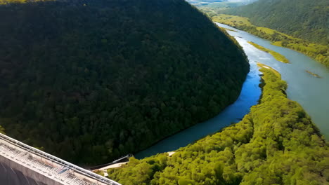aerial view of a large curved dam nestled in a forested landscape