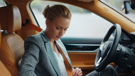 focused woman putting seat belt on at driver seat