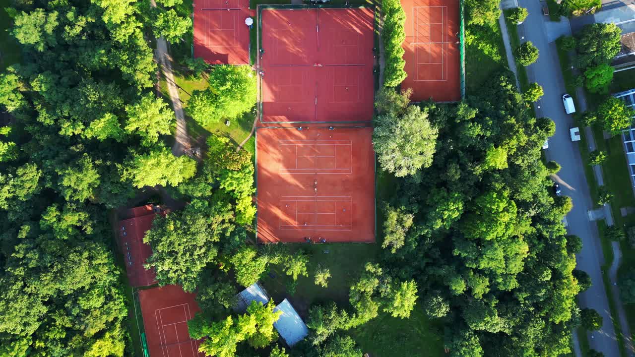 several tennis courts nestled within a dense forest, providing a tranquil escape in the heart of the city Berlin. Gorgeous aerial view flight vertical bird's eye view drone