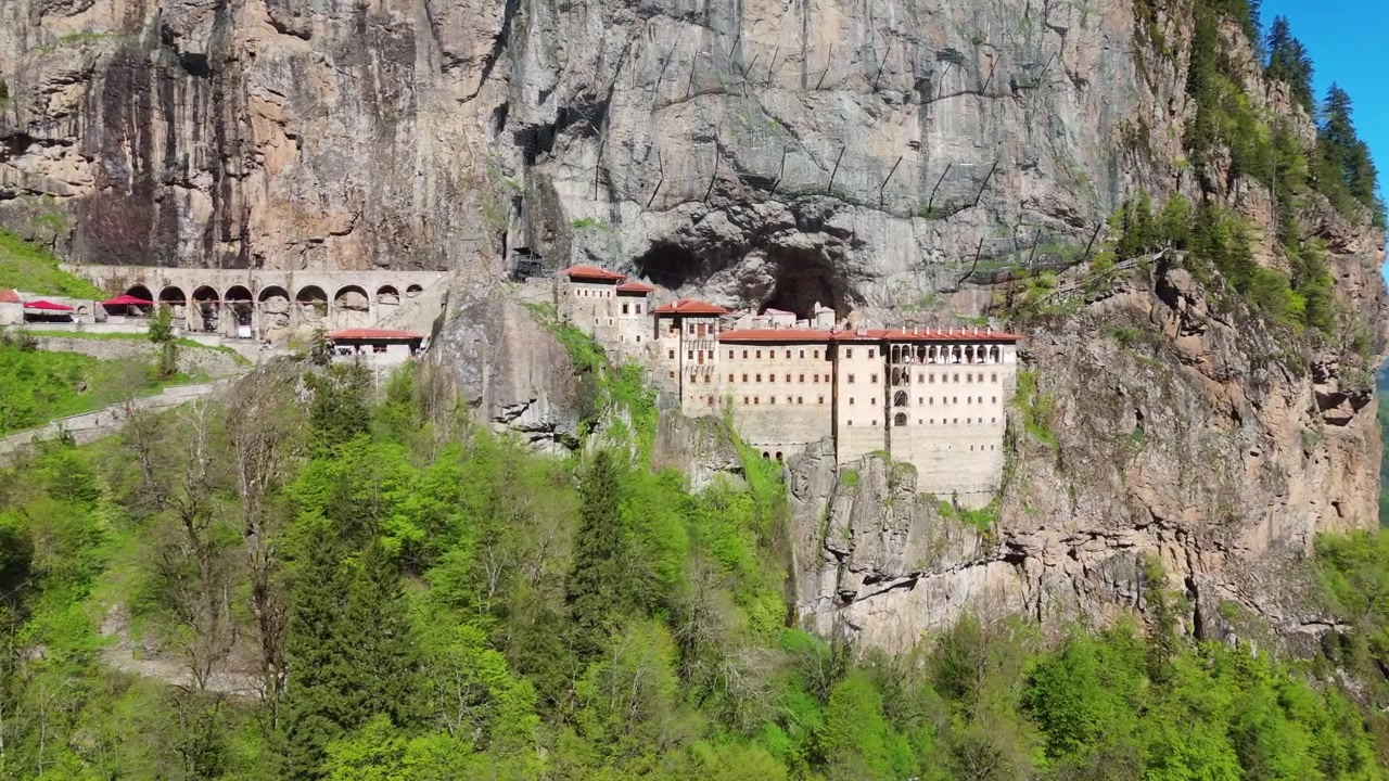 Sumelan luostari, Trabzon. Dronekuva historiallisesta valkoisesta kivikohteesta tiukasti jyrkkää kallioseinämää vasten vihreän laakson yläpuolella, Turkin matkakohde.