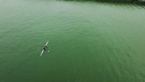 static drone shot of a canoe over a large river on a cloudy day