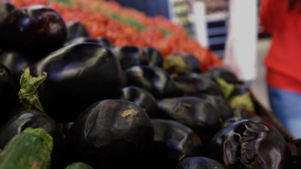 Woman buyer reaching eggplant pile at mart as blue HUD graphics guiding grasping rotating for check