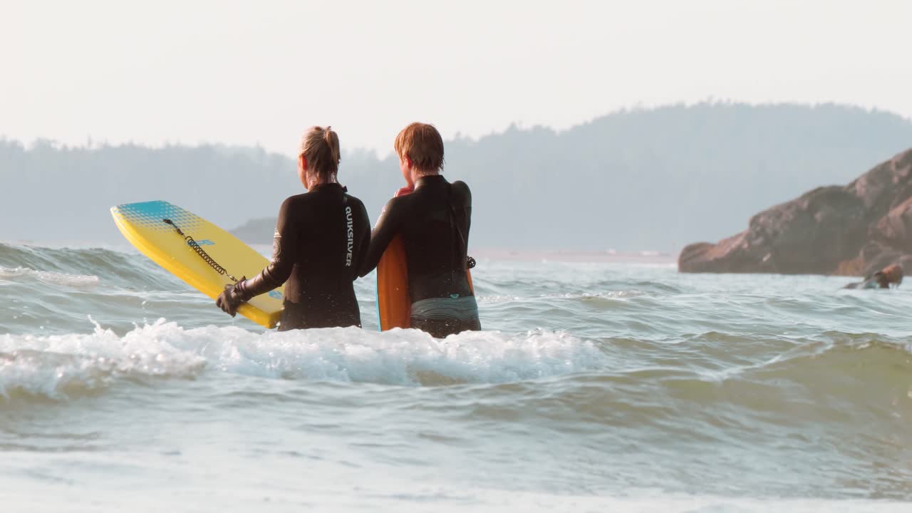 dos personas esperando olas con boogy boards en tofino, columbia británica