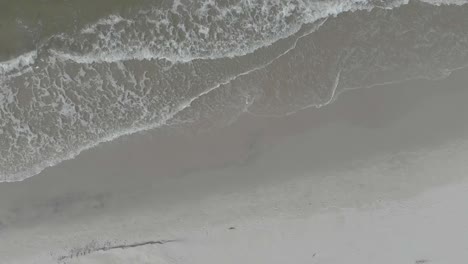 Top-down-aerial-view-on-empty-beach-and-gentle-sea-waves